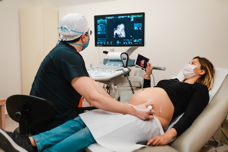 un gynécologue qui pratique une échographie sur une femme enceinte 